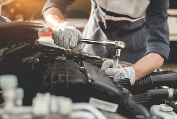 Garage Repair Shop Insurance - Auto Mechanic Working with His Hands and Servicing a Car and Repairing the Engine in the Automotive Workshop with a Wrench